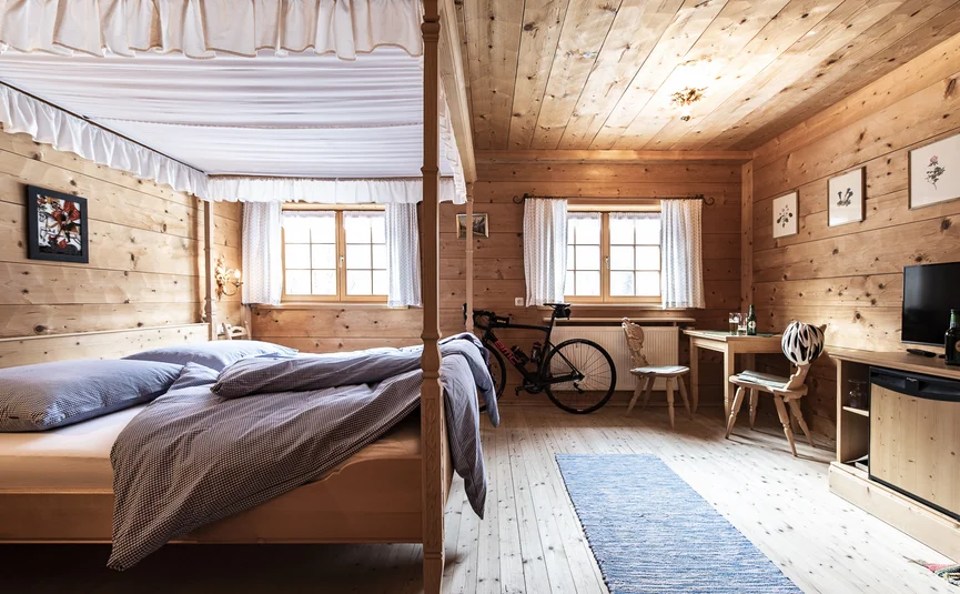 Wooden room with canopy bed, bicycle, and table with chairs