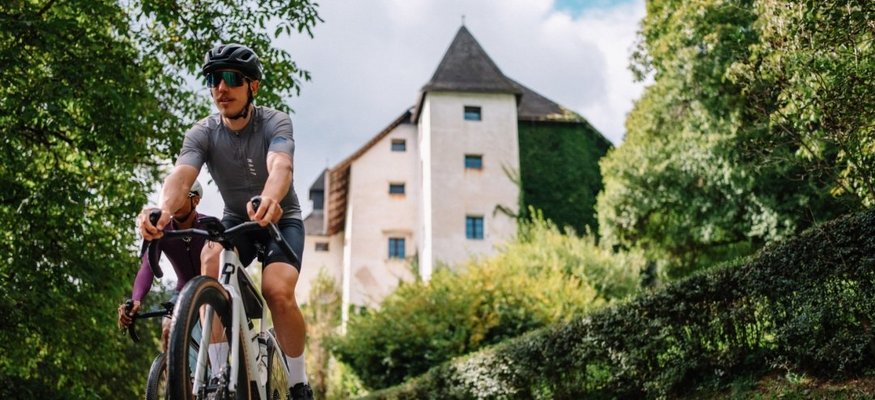 Stift St. Georgen **** © Martin Hoffmann Zwei Radfahrer fahren auf einem Weg mit Schloss und grüner Umgebung