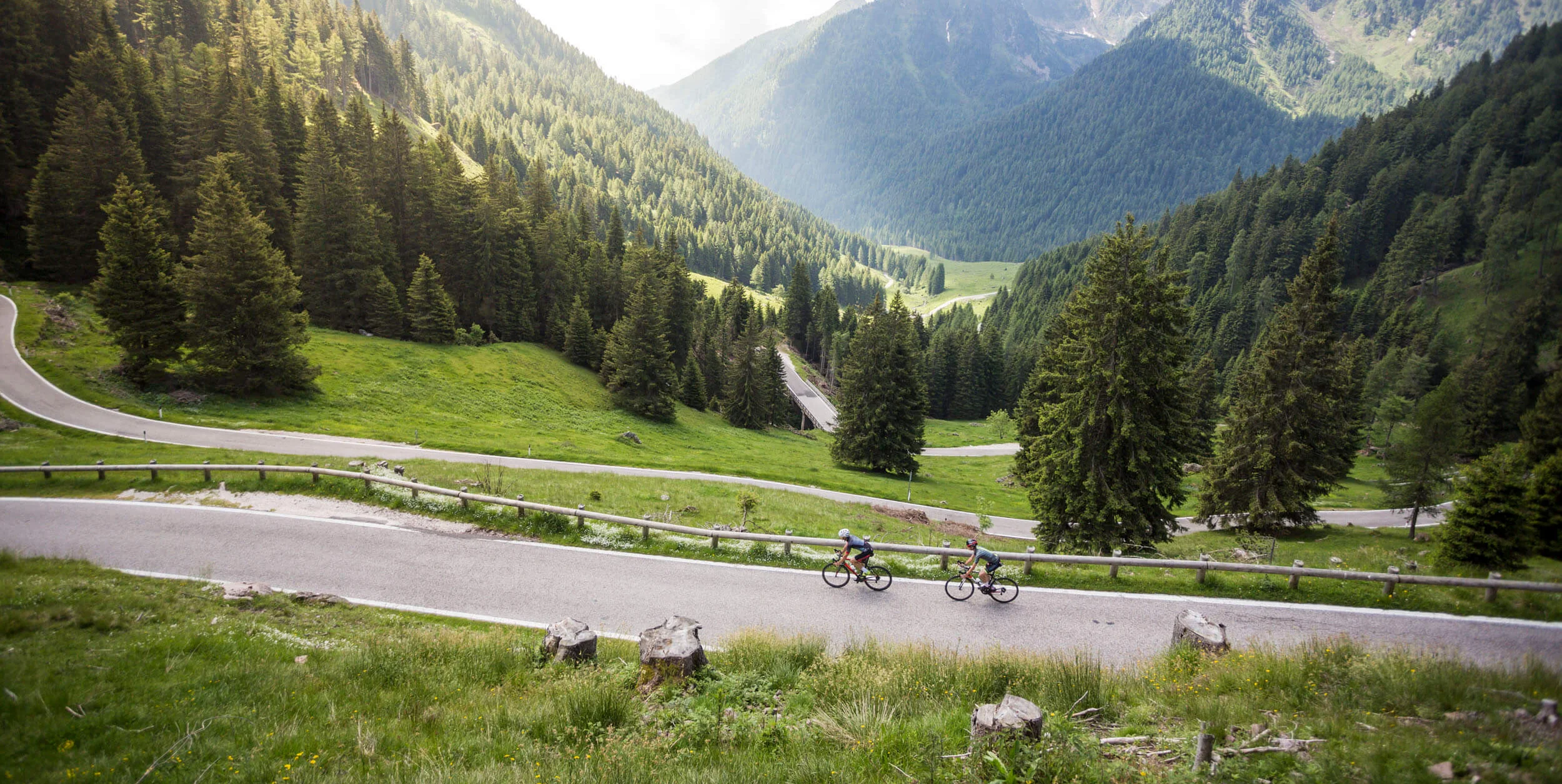 Bikepacking © Heiko Mandl Two cyclists on mountain road with pine forest and mountains in background