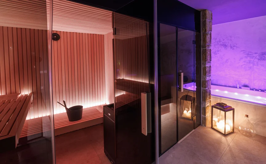 Modern sauna with purple-lit whirlpool and candles