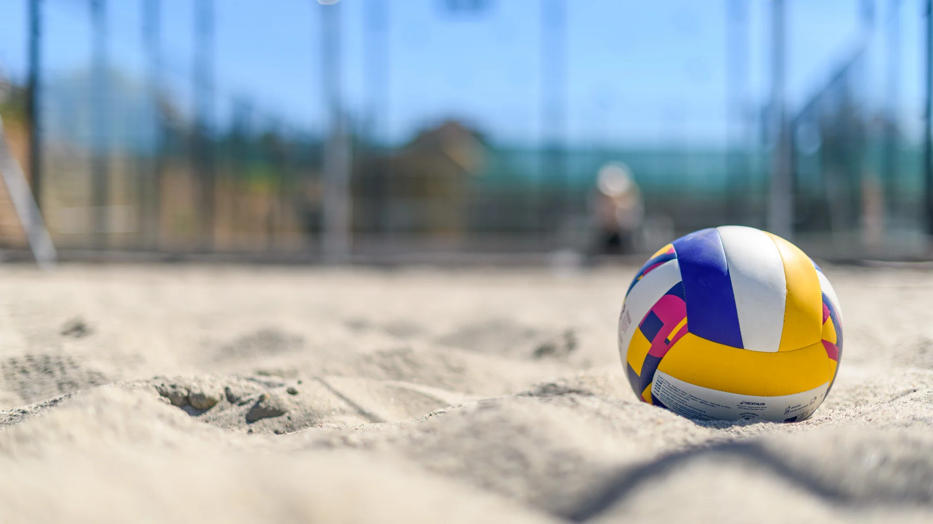 Bunter Volleyball liegt auf Sandplatz im Freien