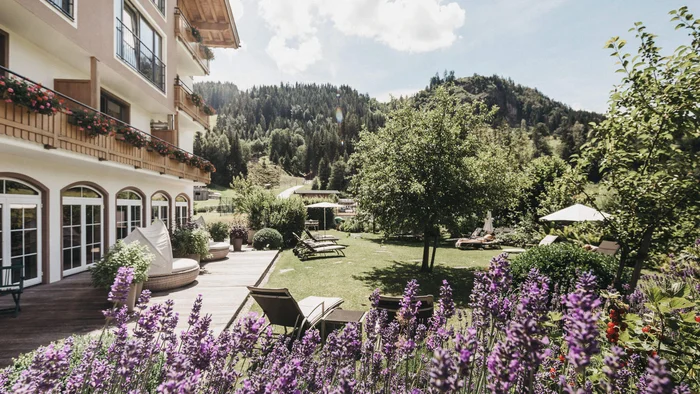 Hotelgarten mit Lavendelblüten, Liegestühlen und Berglandschaft im Hintergrund
