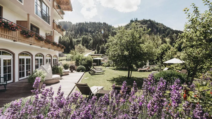 Hotelgarten mit Lavendelblüten, Liegestühlen und Berglandschaft im Hintergrund