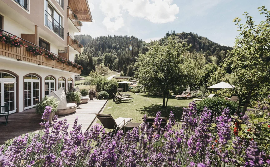 Hotel garden with lavender flowers, lounge chairs, and mountain scenery in the background