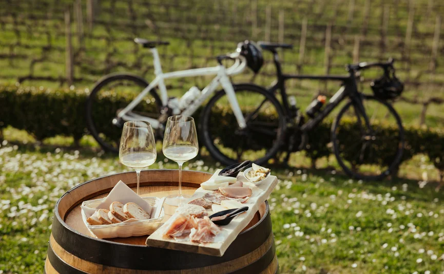 Wine tasting with bread and charcuterie on a barrel outdoors, bicycles in the background
