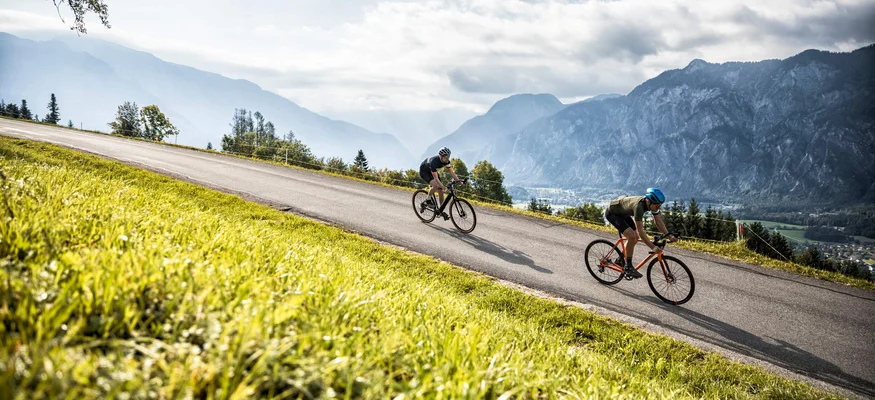 Fuschlseeregion © WOM Medien GMBH - Andreas Meyer Zwei Radfahrer fahren auf einer Straße in bergiger Landschaft bei Tageslicht