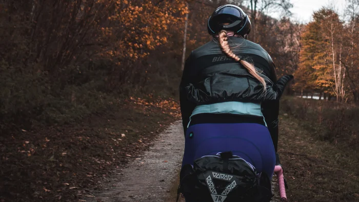 Checklist für das Bikepacking-Abenteuer © Maria Wilke Frau mit Helm fährt Fahrrad auf Waldweg im Herbst