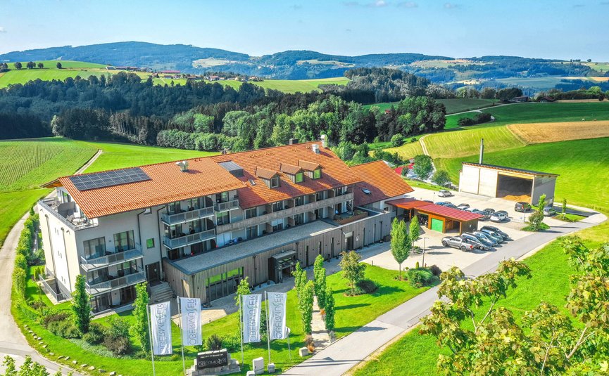 Landrefugium Obermüller ****S © Stefan J. Wolf Photography Gebäude mit rotem Dach und Solarzellen umgeben von grüner Landschaft und Hügeln