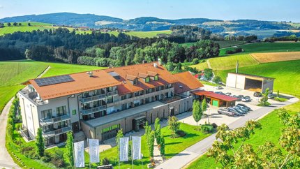Landrefugium Obermüller © Stefan J. Wolf Photography Gebäude mit rotem Dach und Solarzellen umgeben von grüner Landschaft und Hügeln