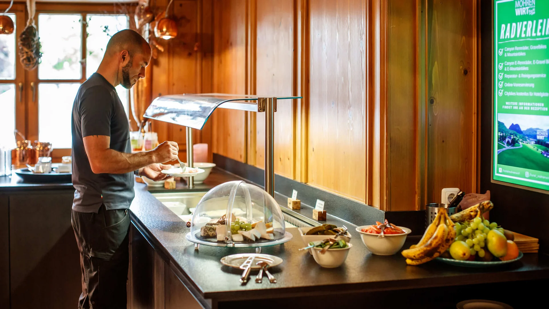 Mann nimmt Essen an einem Buffet in einem Restaurant mit Holzverkleidung