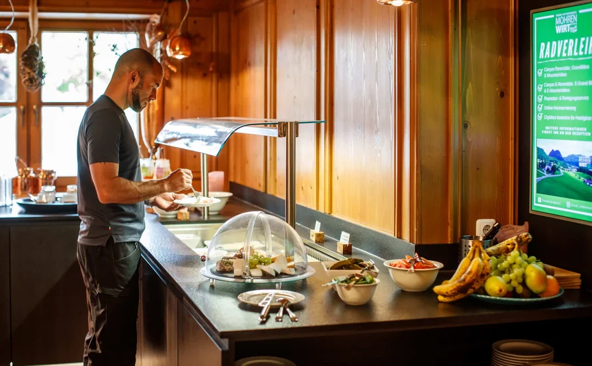Man serving food at a buffet in a wooden-paneled restaurant