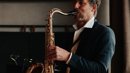 Mann im Anzug spielt Saxophon in einem Raum