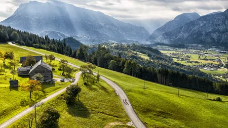 Landschaft mit Berg, grünen Feldern und zwei Radfahrern auf der Straße