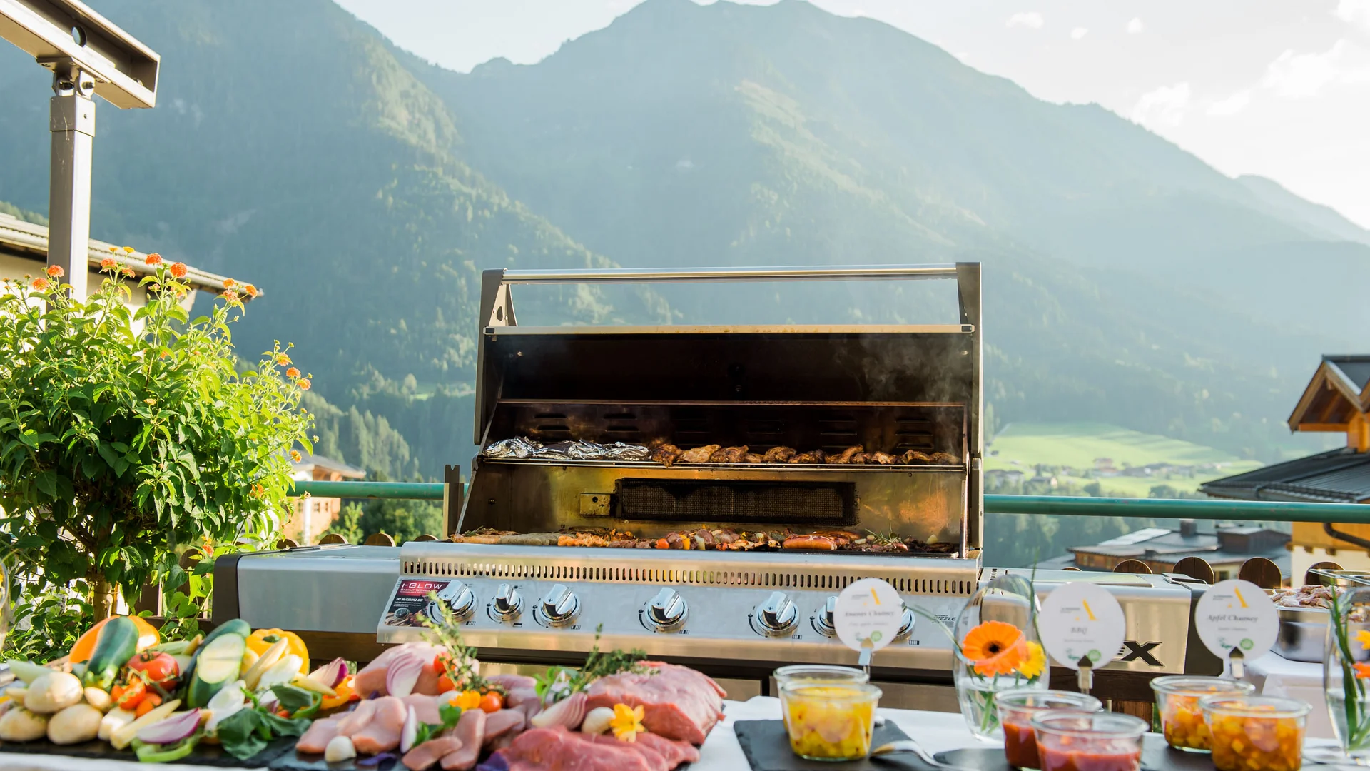 Neue Gravelbike Holidays Hotels 2026 © Matthias Fritzenwallner Grill mit Fleisch, Gemüse und Saucen vor Bergkulisse