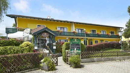 Yellow hotel with green entrance and flowers on the balcony