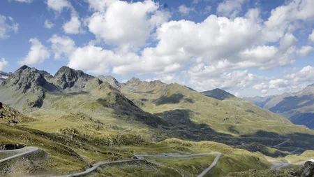 Kurvige Bergstraße in einer hügeligen Landschaft unter blauem Himmel