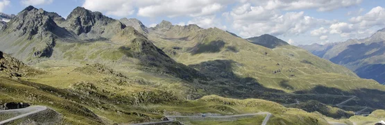 Kurvige Bergstraße in einer hügeligen Landschaft unter blauem Himmel
