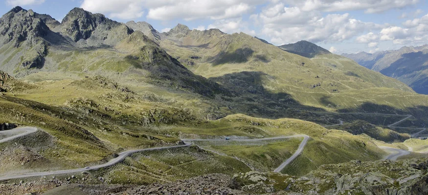 Kurvige Bergstraße in einer hügeligen Landschaft unter blauem Himmel