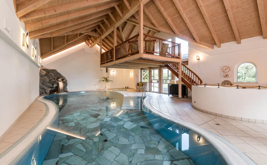 Innenpool mit Steinboden und Holzdecke in einem Wellnessbereich