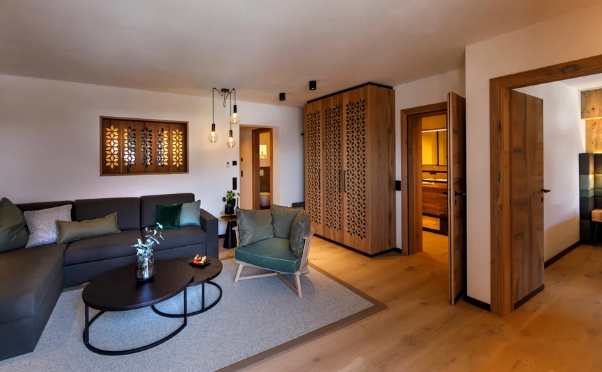 Aktivhotel Alpendorf **** © Atelier Oczlon Gemütliches Wohnzimmer mit Sofa, Sessel, Holzmöbeln und Teppich