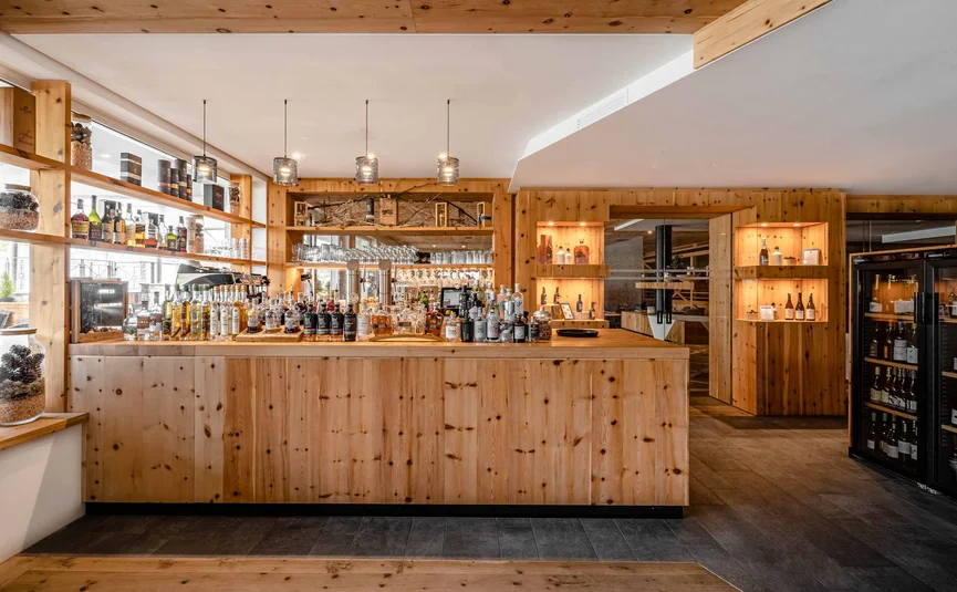 Cristallo Sport & Wellness Hotel **** © Andrea Acler Modern wooden bar with bottles and glassware in a cozy setting