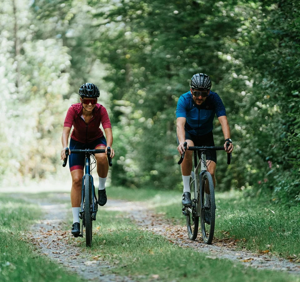 Graveln für Anfänger © Moritz Hübner Zwei Fahrradfahrer auf Waldweg umgeben von grünen Bäumen