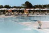 Modern pool with water fountain and lounge chairs under white umbrellas