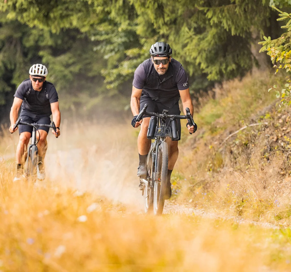 Zwei Männer fahren Mountainbikes auf einem Naturweg im Wald