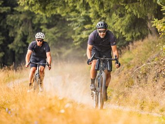 Zwei Männer fahren Mountainbikes auf einem Naturweg im Wald