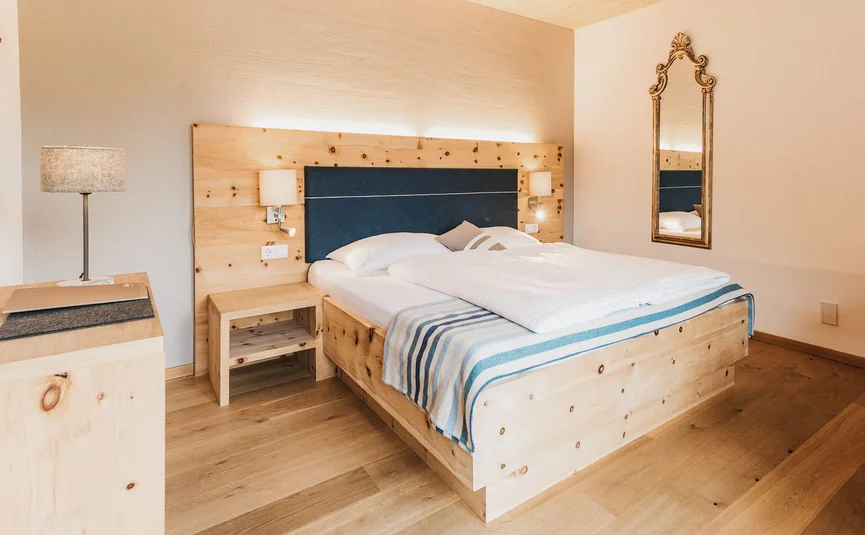 Bedroom with wooden furniture, double bed, and decorative wall mirror