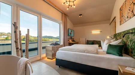 Modern eingerichtetes Schlafzimmer mit großem Fenster und Landschaftsblick