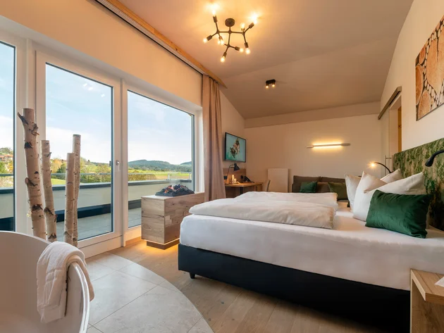 Modern eingerichtetes Schlafzimmer mit großem Fenster und Landschaftsblick