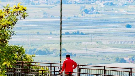 Person mit Fahrrad auf Aussichtspunkt mit Blick auf Tal und Berge