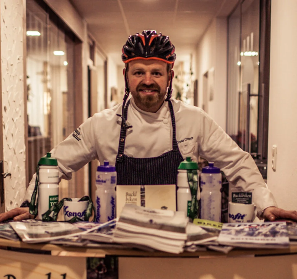 Am Krumbacherhof biked der Wirt! © Robert Weber Mann mit Fahrradhelm hinter Infostand für Bucklbiken und Krumbacherhof