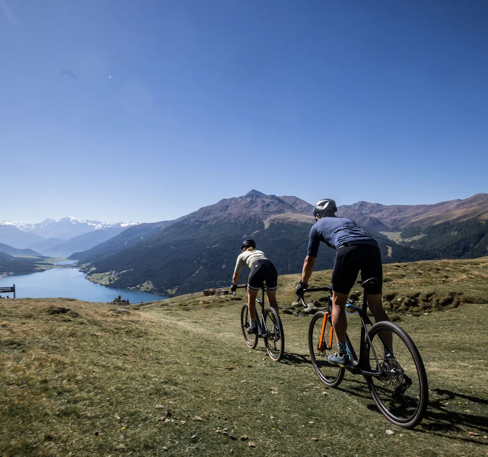 Ein Gravel-Wochenende in Nauders-Reschensee © Heiko Mandl Zwei Radfahrer fahren auf einem Bergpfad mit Blick auf Tal und Berge