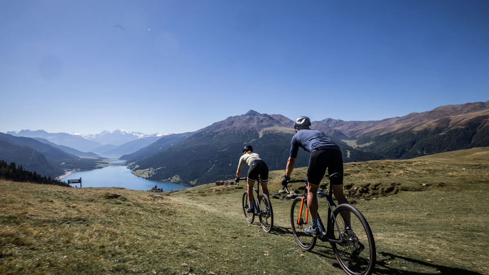 Ein Gravel-Wochenende in Nauders-Reschensee © Heiko Mandl Zwei Radfahrer fahren auf einem Bergpfad mit Blick auf Tal und Berge