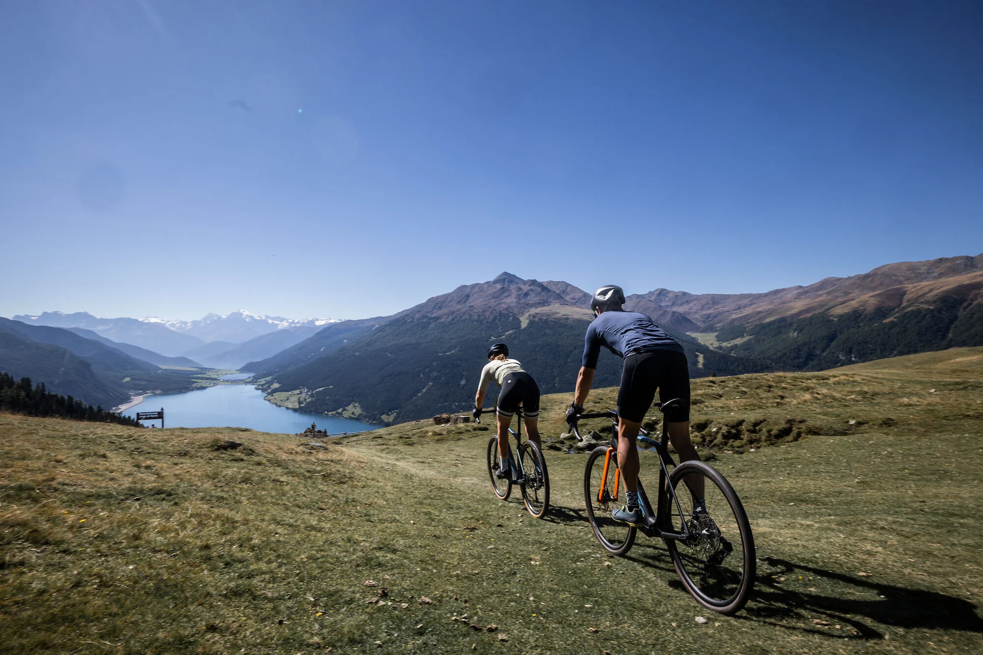 Gravelbike Holidays © Heiko Mandl Zwei Radfahrer fahren auf einem Bergpfad mit Blick auf Tal und Berge