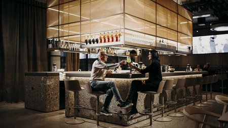 Zwei Personen stoßen in einer modernen Bar mit Drinks an