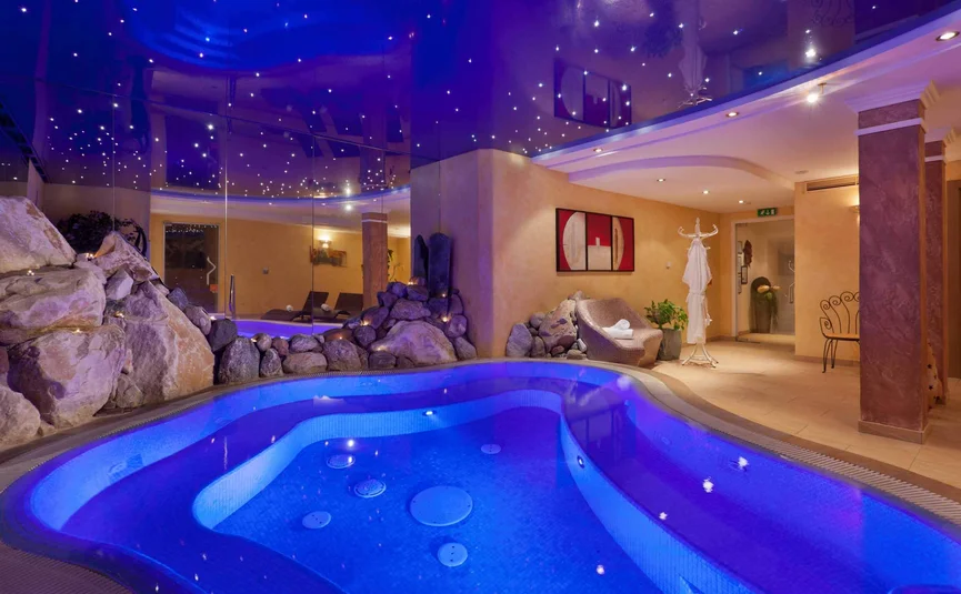 Indoor hot tub with illuminated pool and starry ceiling
