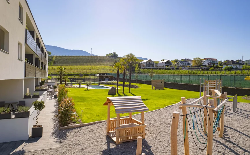 Modern playground and pool next to apartment building with vineyard in the background