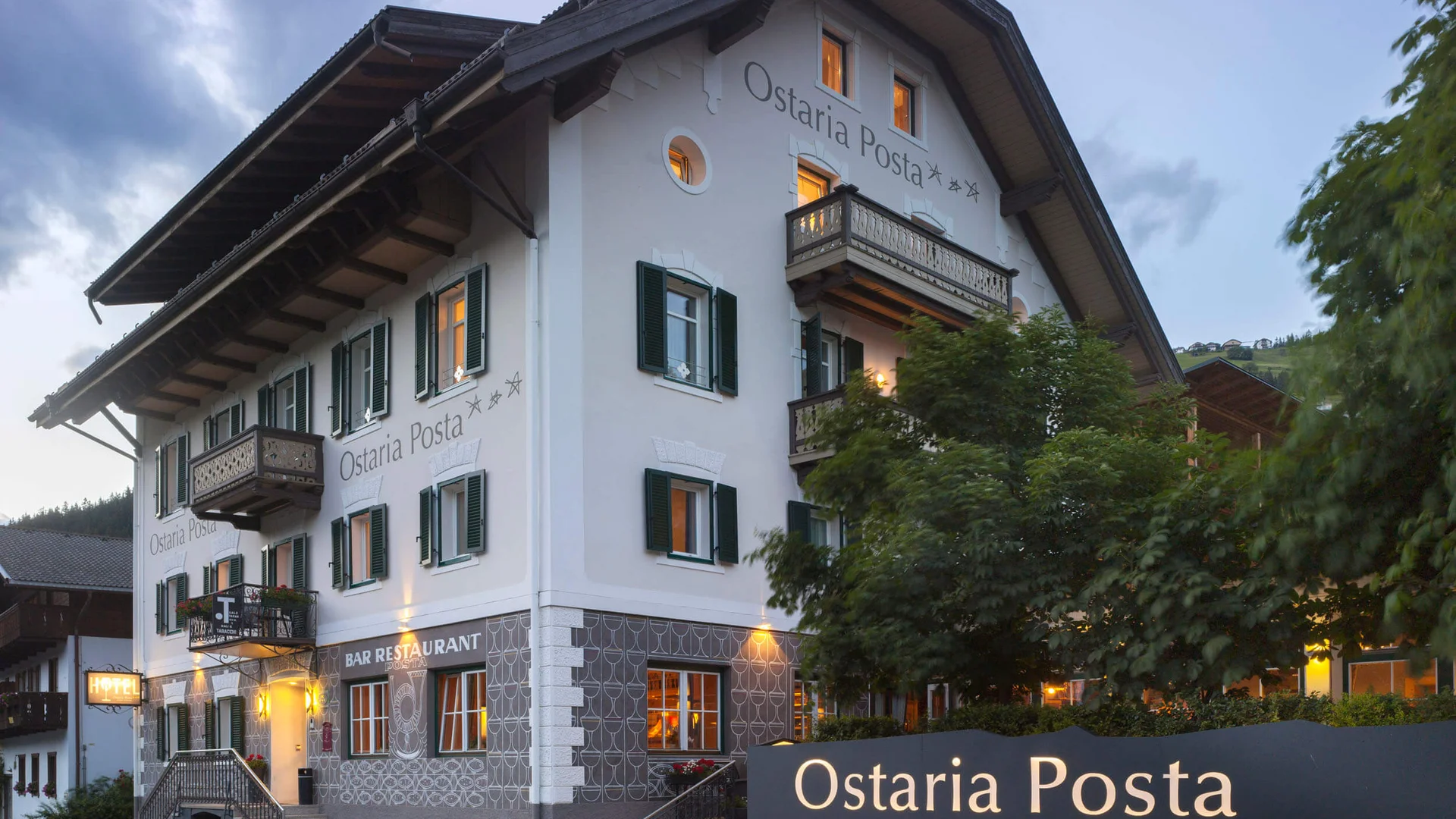 Gravel & Genuss am Kronplatz © Watzek Photografie Aussenansicht des Ostaria Posta Hotel und Restaurants bei Abenddämmerung