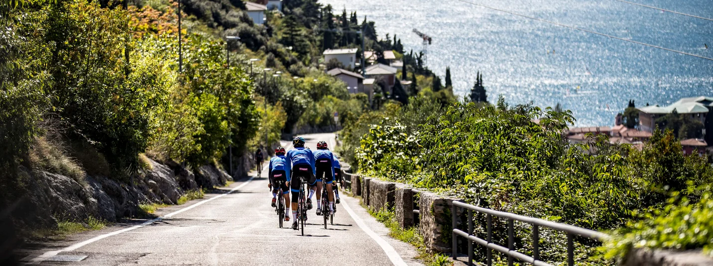 Maxxis Gravel Garda Trentino © Castelli Group of cyclists on road overlooking lake and mountains in background