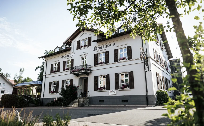 Posthorn Hotel-Restaurant © Dimitri Dell Weißes Gasthaus Posthorn mit dunklen Fensterläden, eingerahmt von Bäumen