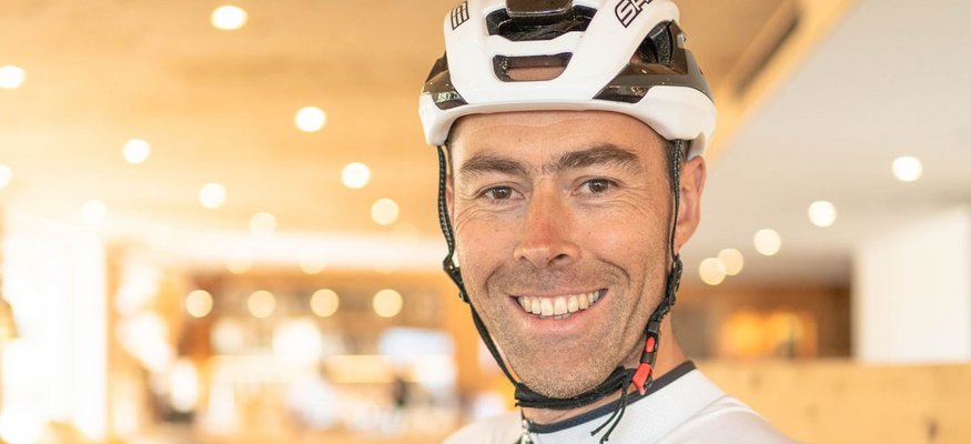 Lächelnder Radfahrer mit Helm in Sport- und Wellnesshotelumgebung