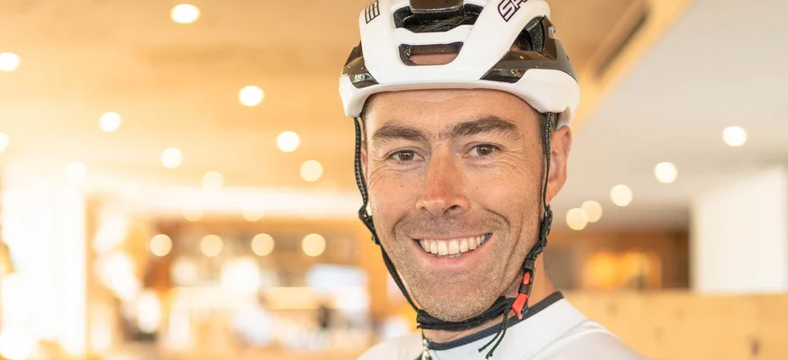 Lächelnder Radfahrer mit Helm in Sport- und Wellnesshotelumgebung