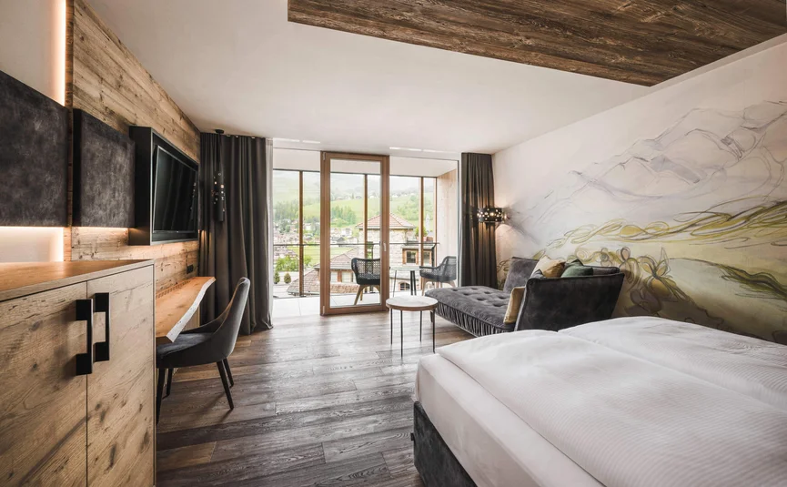 Modern hotel room with wooden furniture and balcony overlooking mountains