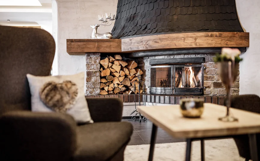 Gemütlicher Raum mit Kamin, Holzstapel und bequemen Sesseln