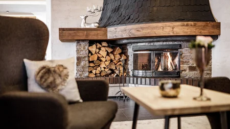 Gemütlicher Raum mit Kamin, Holzstapel und bequemen Sesseln