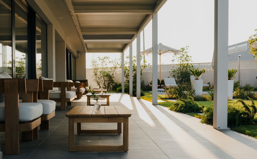 Moderne Terrasse mit Holzmöbeln und Sonnenschirm im Garten