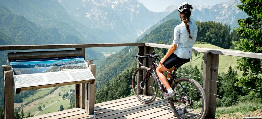 Frau mit Fahrrad blickt auf Bergpanorama von Aussichtsplattform